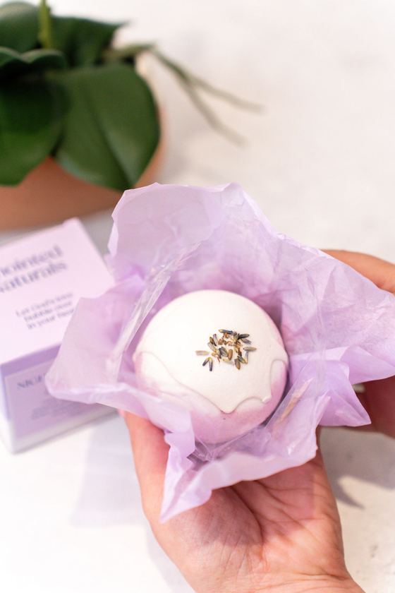 A bath bomb nestled in lilac tissue paper