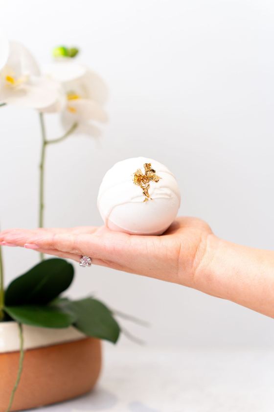 Gold-leaf bath bomb held in an open hand
