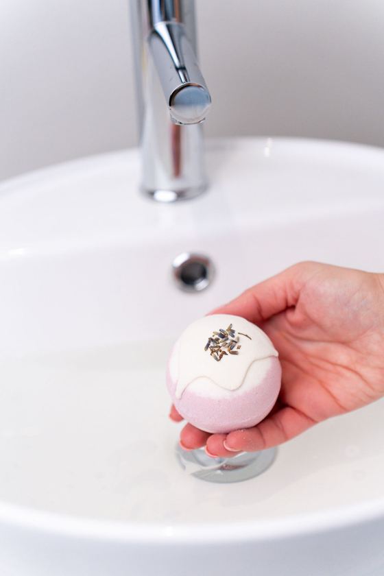 Pink bath bomb held over the basin