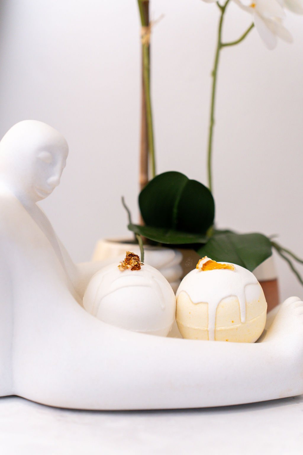 Two bath bombs resting in a white ceramic dish